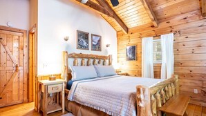 A wooden cabin bedroom with a bed, bedside tables, and a bench.