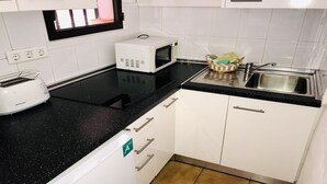 A kitchen with white cabinets, a black countertop, a white toaster, a microwave, and a sink. - Welooveyou Libra Starlight A42 (Costa Calma (incl. Urbanización Cañada del Río))