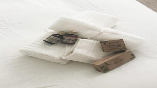 A white bed with folded towels and two small bottles of cream on it. - refuge for unforgettable days in Agaete WIFI Fiber (Agaete)
