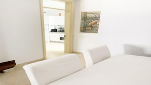 Ein Zimmer mit einem Bett, einem Bild an der Wand und Blick auf eine Küche durch eine offene Tür.
