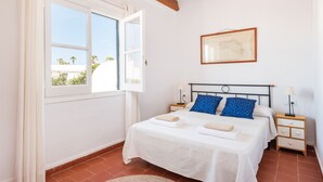 Une chambre à coucher avec un lit, deux tables de chevet, une fenêtre et une carte encadrée accrochée au mur.