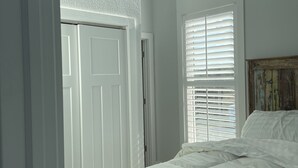 A bedroom with a bed, a window with blinds, an air conditioning unit, and a door. - Romantic Little Getaway in 4X4 beach (Corolla)
