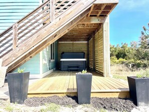 A wooden deck with a bench, a hot tub, and a staircase leading to a covered area. - Romantic Little Getaway in 4X4 beach (Corolla)