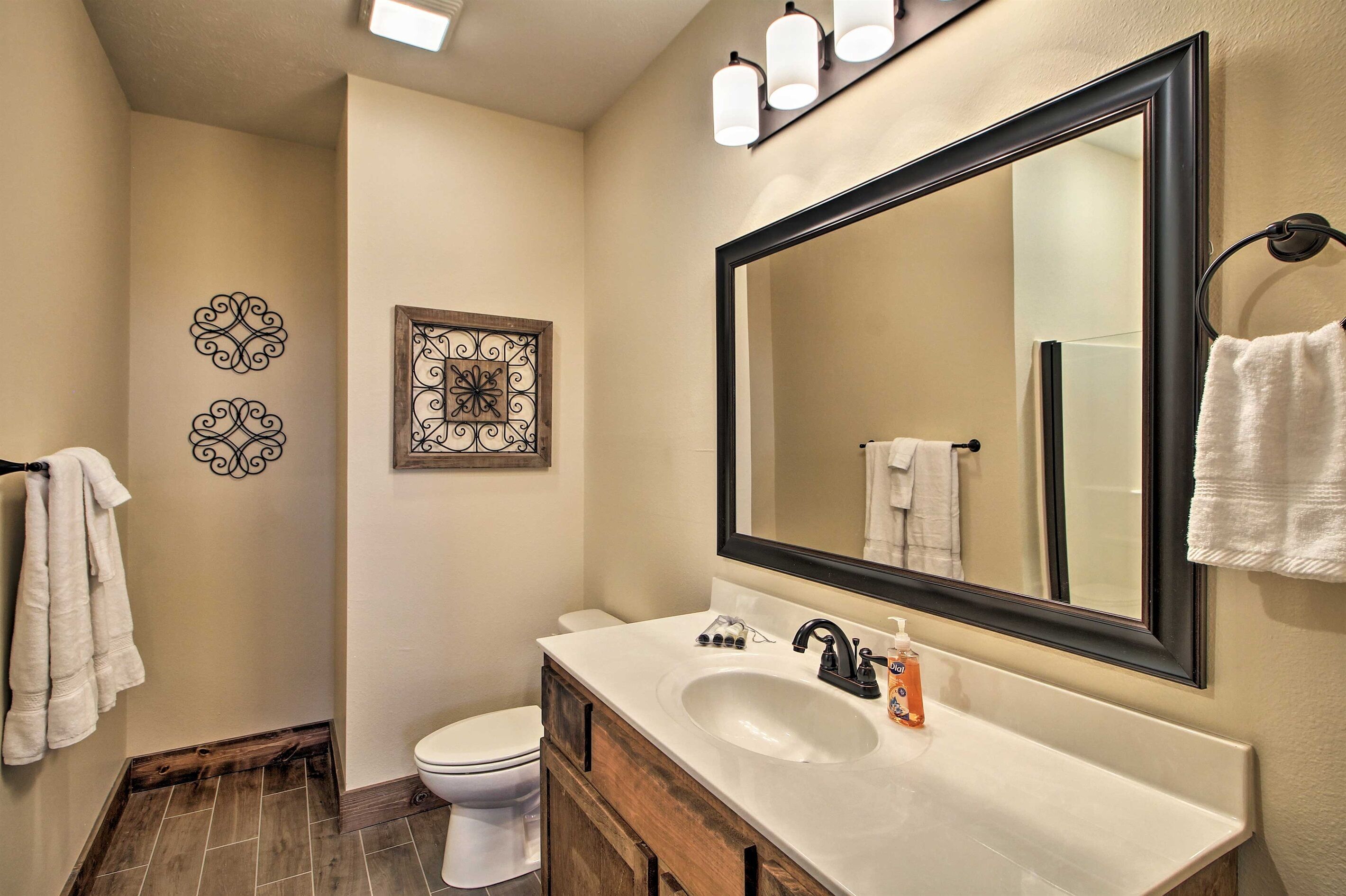 A bathroom with a white sink, a large mirror, and two decorative wall pieces.