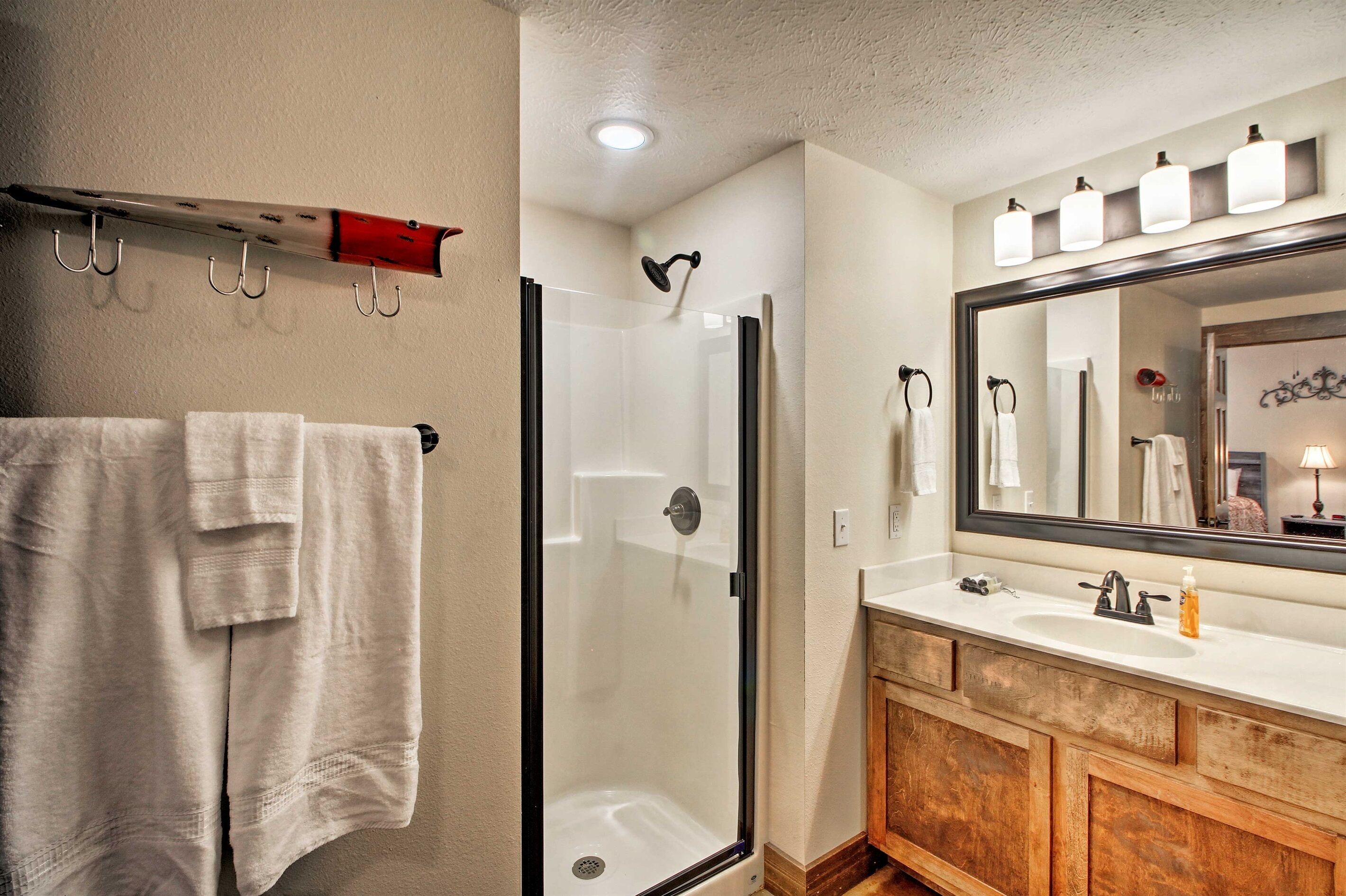 A bathroom with a glass-enclosed shower, a large mirror, and a wooden vanity.