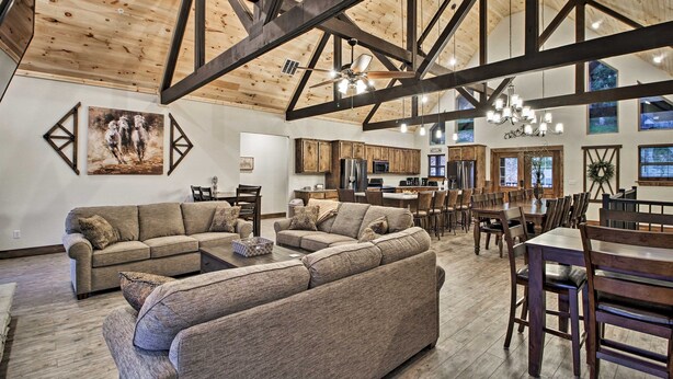 A spacious living room with a large sectional sofa, wooden beams on the ceiling, and a dining area with wooden tables and chairs. - Lake View | Game Room | King Beds | Hot Tub | Pool (Branson)
