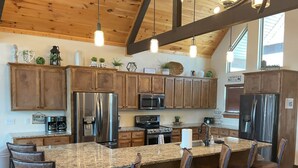 A kitchen with wooden cabinets, stainless steel appliances, a granite countertop, and pendant lighting. - Lake View | Game Room | King Beds | Hot Tub | Pool (Branson)