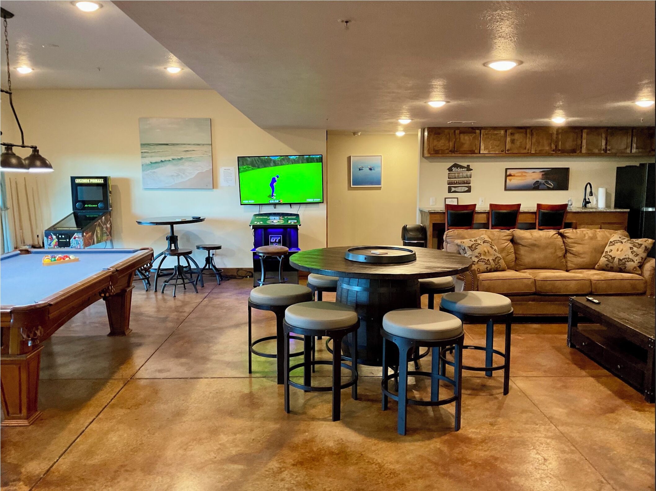 A living room with a pool table, a television, and a bar area with stools.
