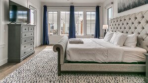 Een slaapkamer met een bed, een dressoir, een plafondventilator en een schilderij aan de muur.