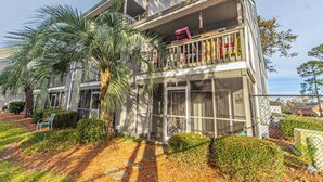 A two-story building with a balcony, a palm tree, and a well-maintained garden. - Golf Colony at Deerfield 33-I (Myrtle Beach)