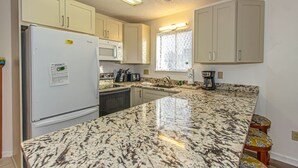 A kitchen with a refrigerator, stove, microwave, sink, and a window. - Golf Colony at Deerfield 33-I (Myrtle Beach)