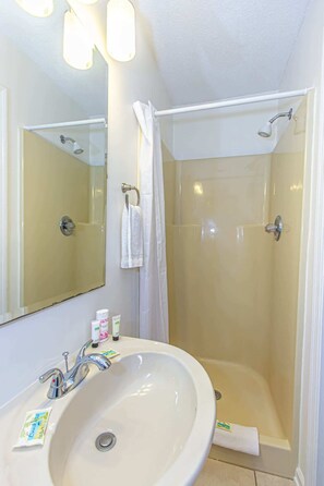 Une salle de bain équipée d’un lavabo, d’un miroir, d’une douche et d’un porte-serviettes.