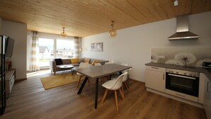 A modern kitchen with a dining area, wooden flooring, and a view to the outside. - Ferienwohnung Pusteblume Beilngries (Beilngries)