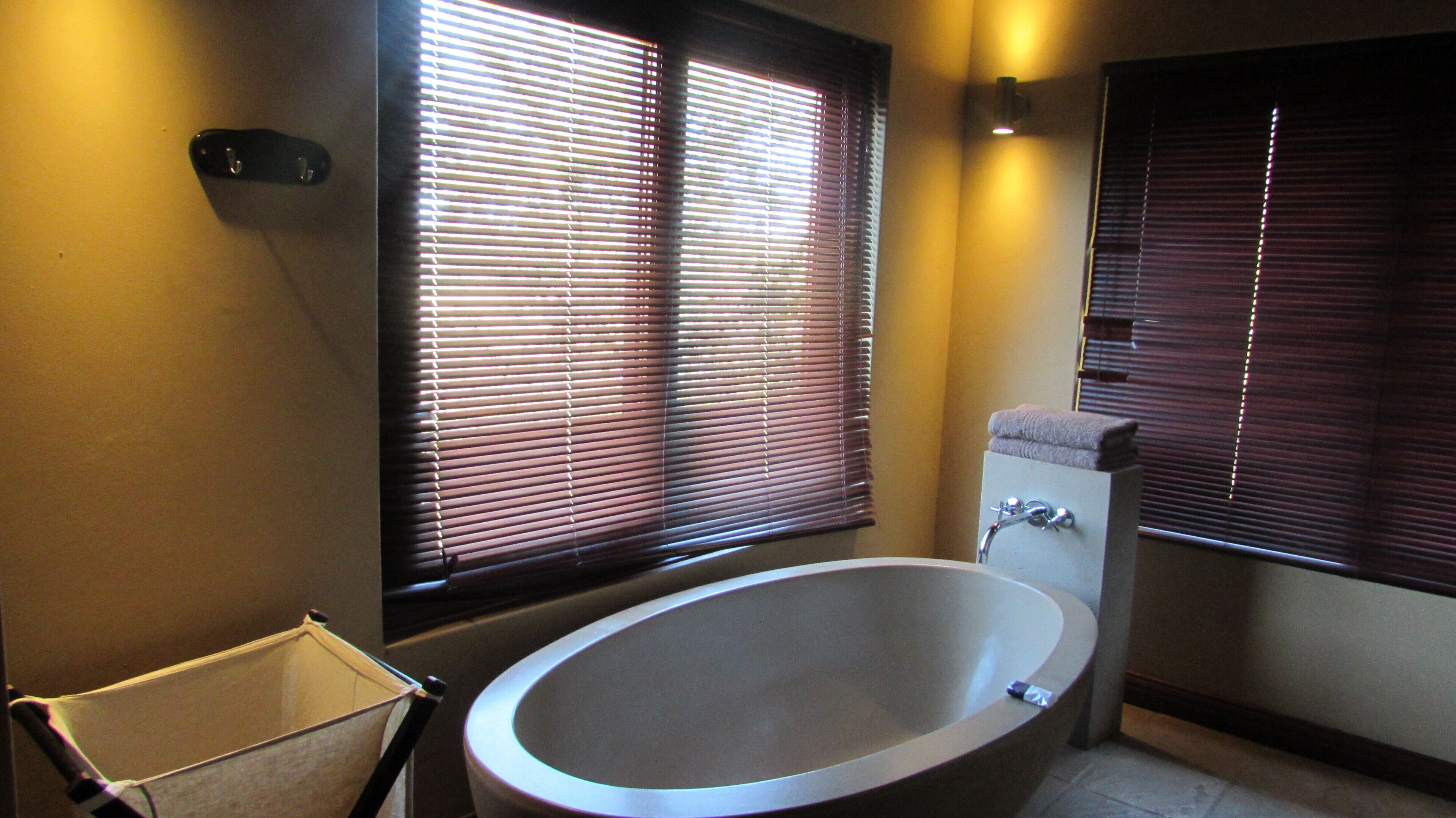 A bathroom with a freestanding bathtub, a towel rack, and a window with blinds.