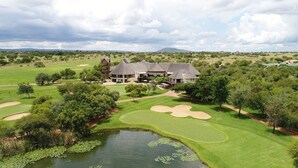 Una extensa propiedad con campo de golf, estanque y una casa grande con varias construcciones.