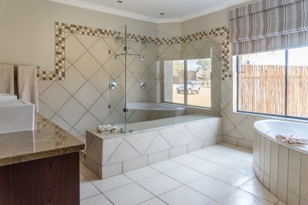 A modern bathroom with a glass-enclosed shower, a freestanding bathtub, and a vanity with a marble countertop.
