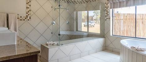 A modern bathroom with a glass-enclosed shower, a freestanding bathtub, and a vanity with a marble countertop.