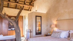 Un dormitorio con una cama grande, un armario de madera, un espejo y un tronco de árbol.