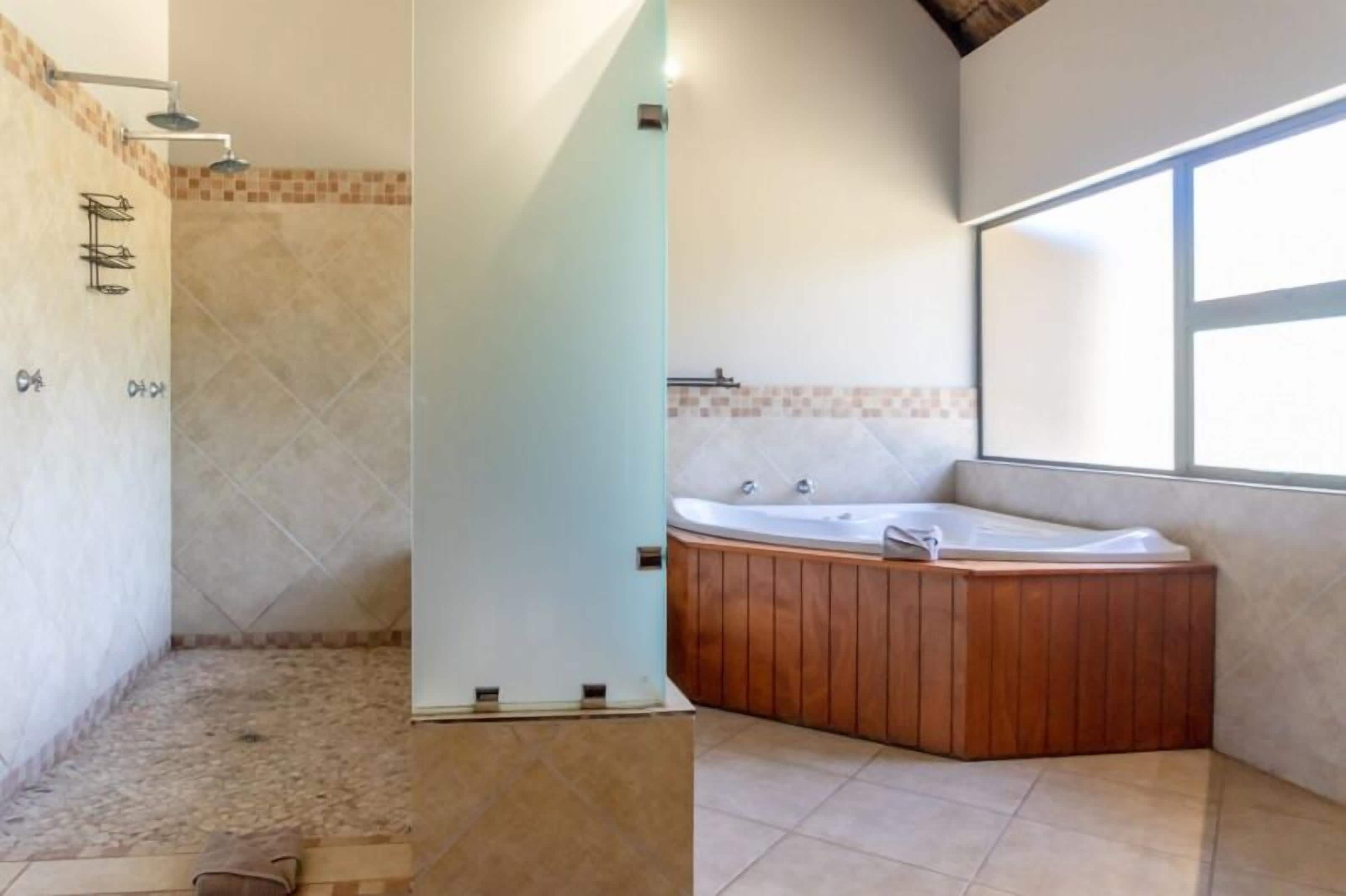 Un baño con ducha, bañera y ventana que deja entrar luz natural.
