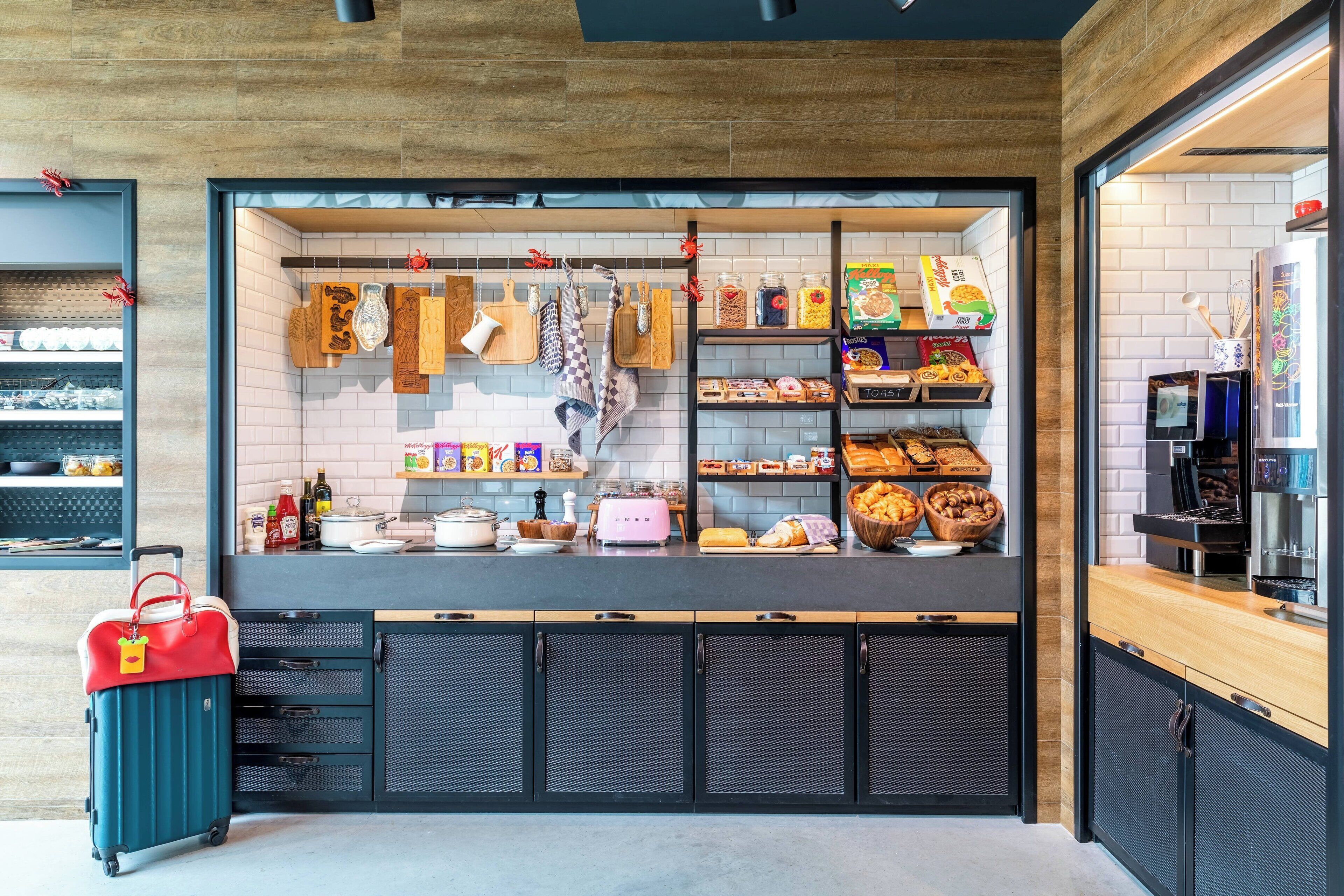 Una cuina moderna amb forn de mur i una màquina de cafè, i diversos aliments exposats a prestatges.