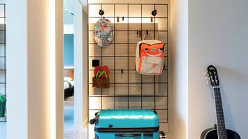 Ein Zimmer mit einem an der Wand befestigten Gepäckträger, der einen blauen Koffer, eine Gitarre und eine Tasche beherbergt.