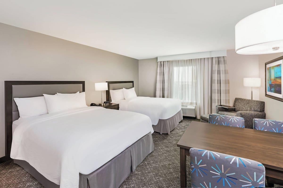 Ein Hotelzimmer mit zwei Betten, einem Esstisch und einer Sitzecke.