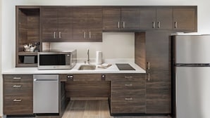 A modern kitchen with dark wood cabinets, stainless steel appliances, and a white countertop.