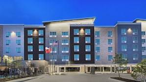A multi-story hotel with a modern design, featuring a prominent entrance and a flag display.