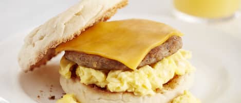 A breakfast sandwich with sausage, cheese, and scrambled eggs on a biscuit.