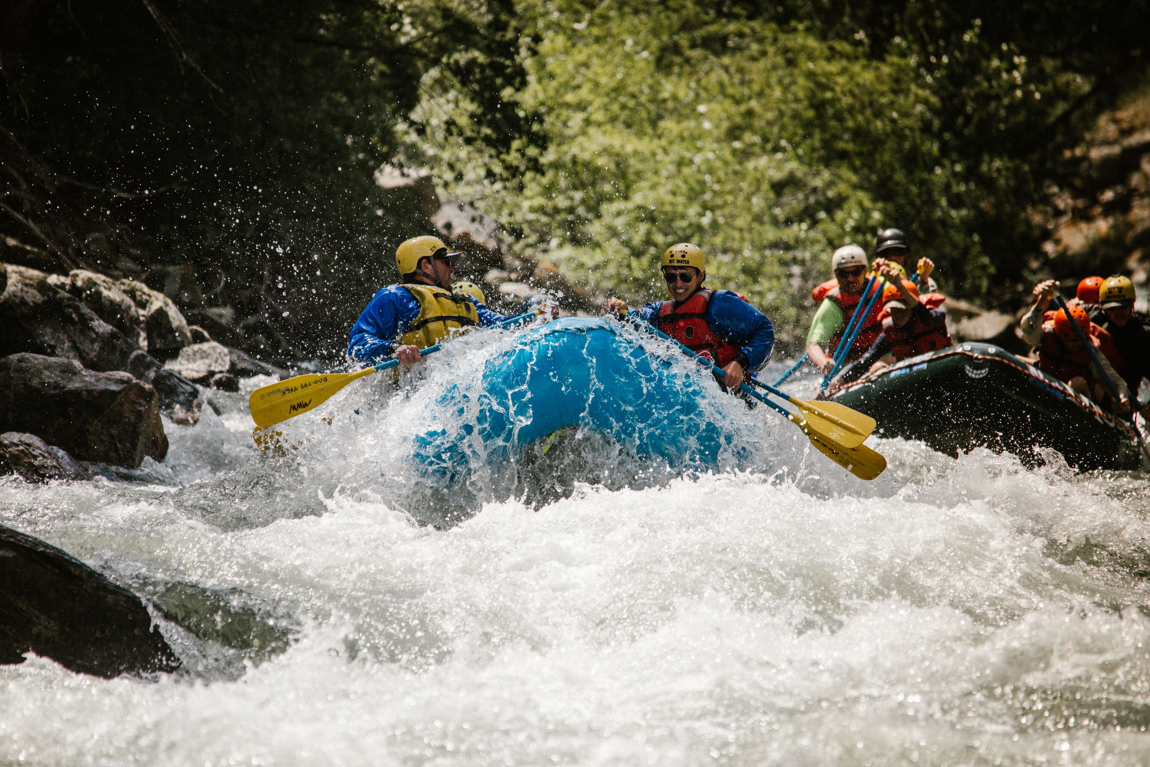A group of people in a blue raft navigating through a river with rapids.