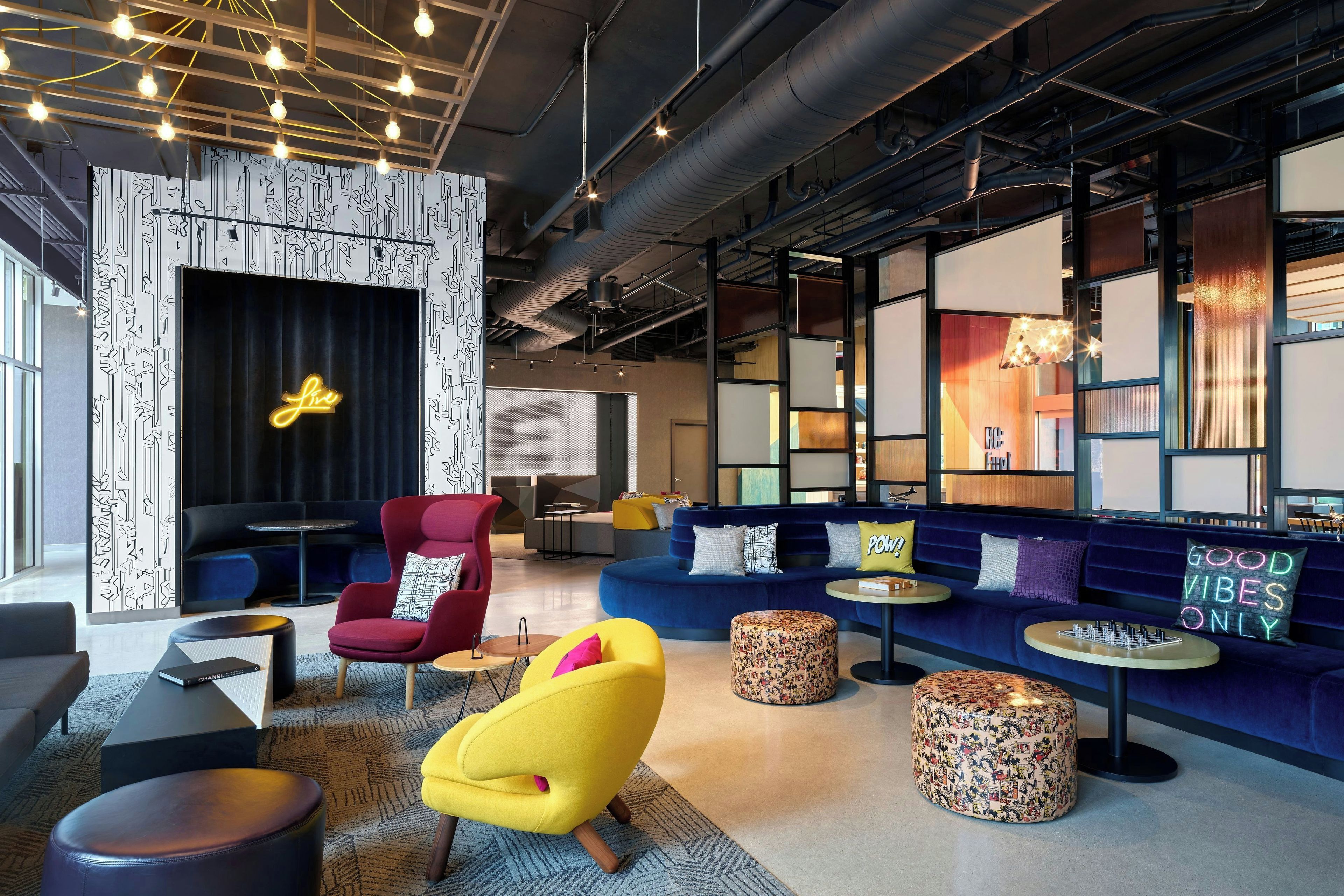A modern lounge area with seating, a neon sign, and a patterned wall.