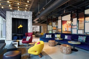 A modern lounge area with seating, a neon sign, and a patterned wall. - Aloft by Marriott Trophy Club Westlake (Roanoke)