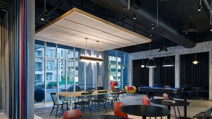 A modern lounge area with a pool table, comfortable seating, and large windows offering views of the city. - Aloft by Marriott Trophy Club Westlake (Roanoke)