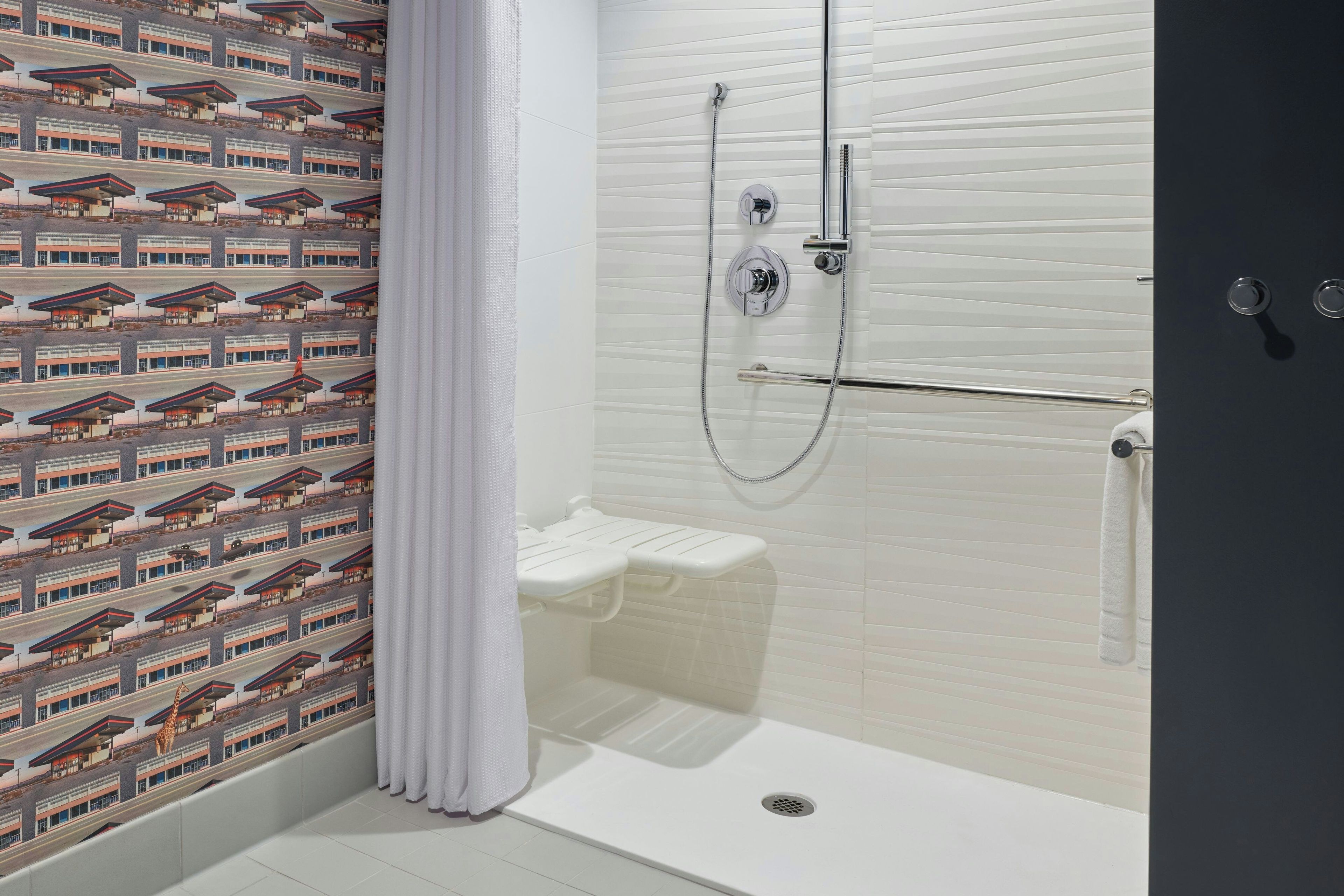Une douche avec un mur recouvert de carreaux blancs, une porte en verre et un pommeau de douche.