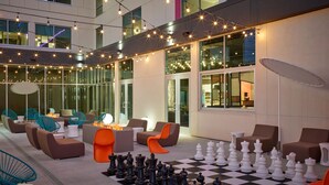 An outdoor seating area with chess tables, lounge chairs, and string lights. - Aloft by Marriott Trophy Club Westlake (Roanoke)