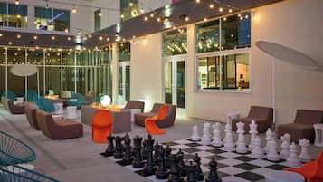 An outdoor seating area with modern furniture, a chessboard, and string lights.