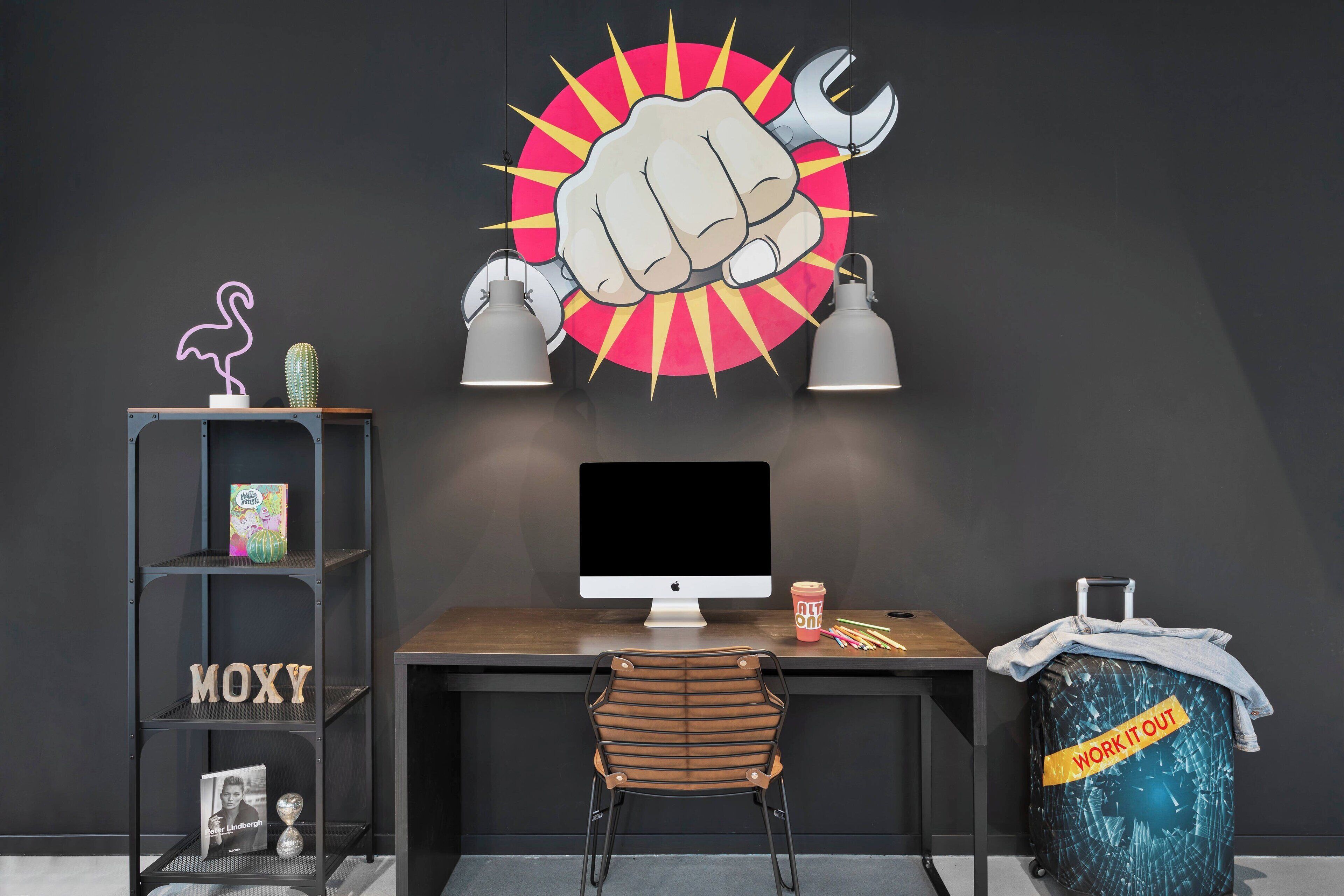 Un espacio de trabajo moderno con escritorio, ordenador y un cartel motivacional.