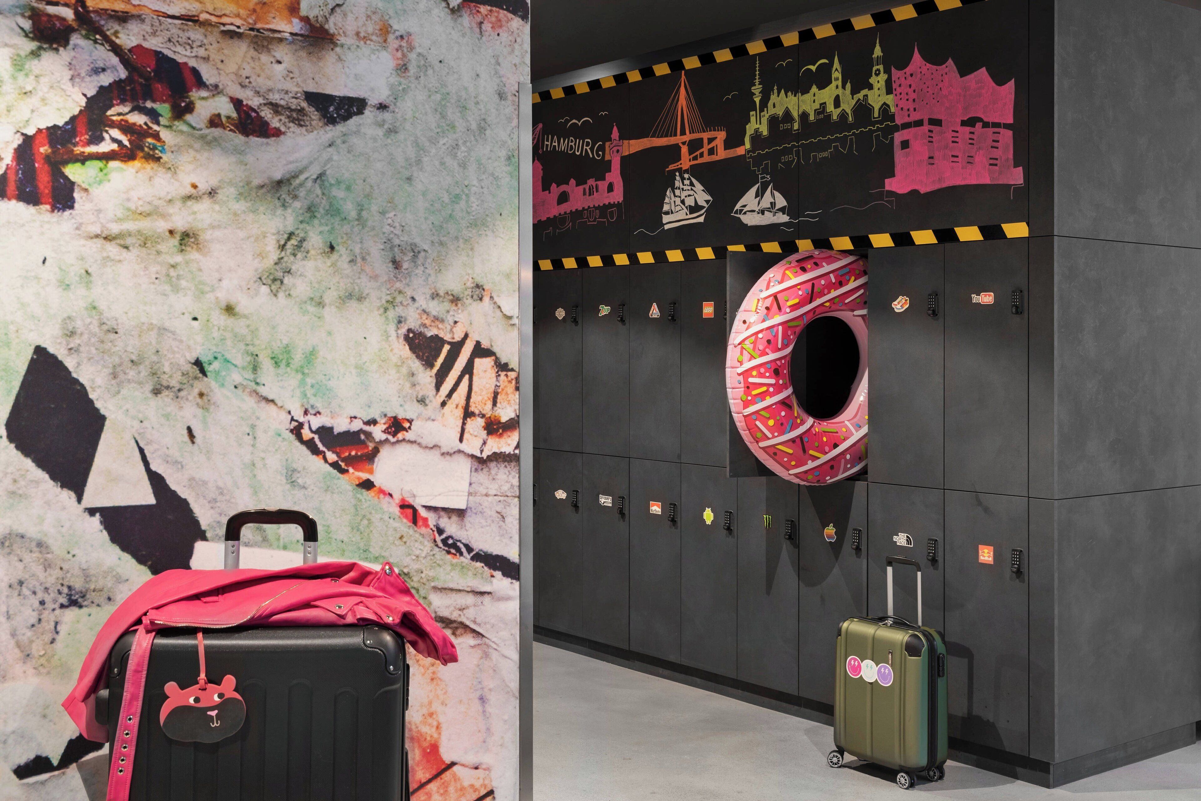 Un mur orné d’une fresque colorée et un espace de stockage de bagages avec des casiers.