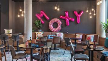 A modern lounge area with seating, tables, and decorative elements like balloons and a donut-shaped decoration.