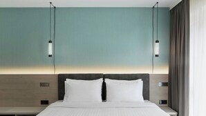 A hotel room with a large bed, two bedside tables, a nightstand, a headboard, and two pendant lights. - Residence Inn by Marriott Hamburg Altona (Hamburg)