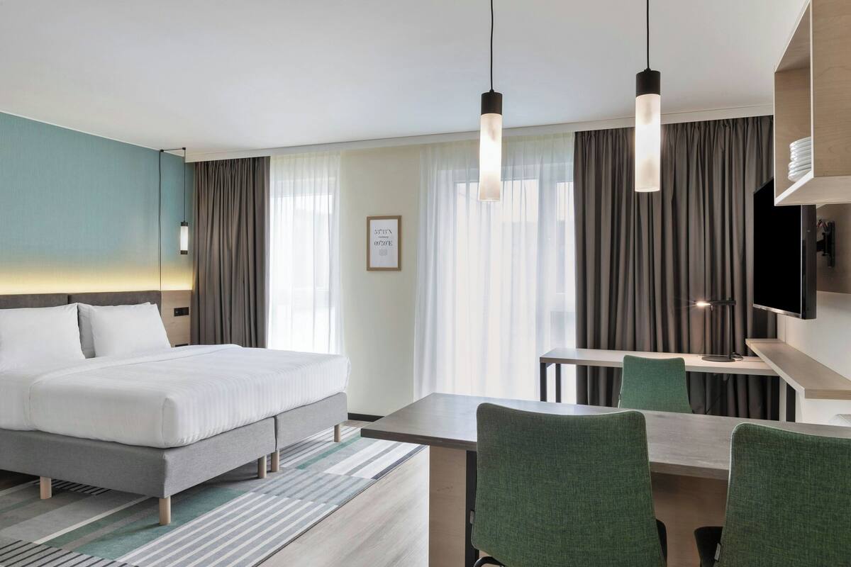 A hotel room with a bed, a desk, and a TV.