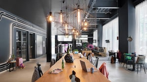 A modern office space with a long wooden table, multiple chairs, and a unique hanging light fixture. - Moxy Milton Keynes (Milton Keynes)