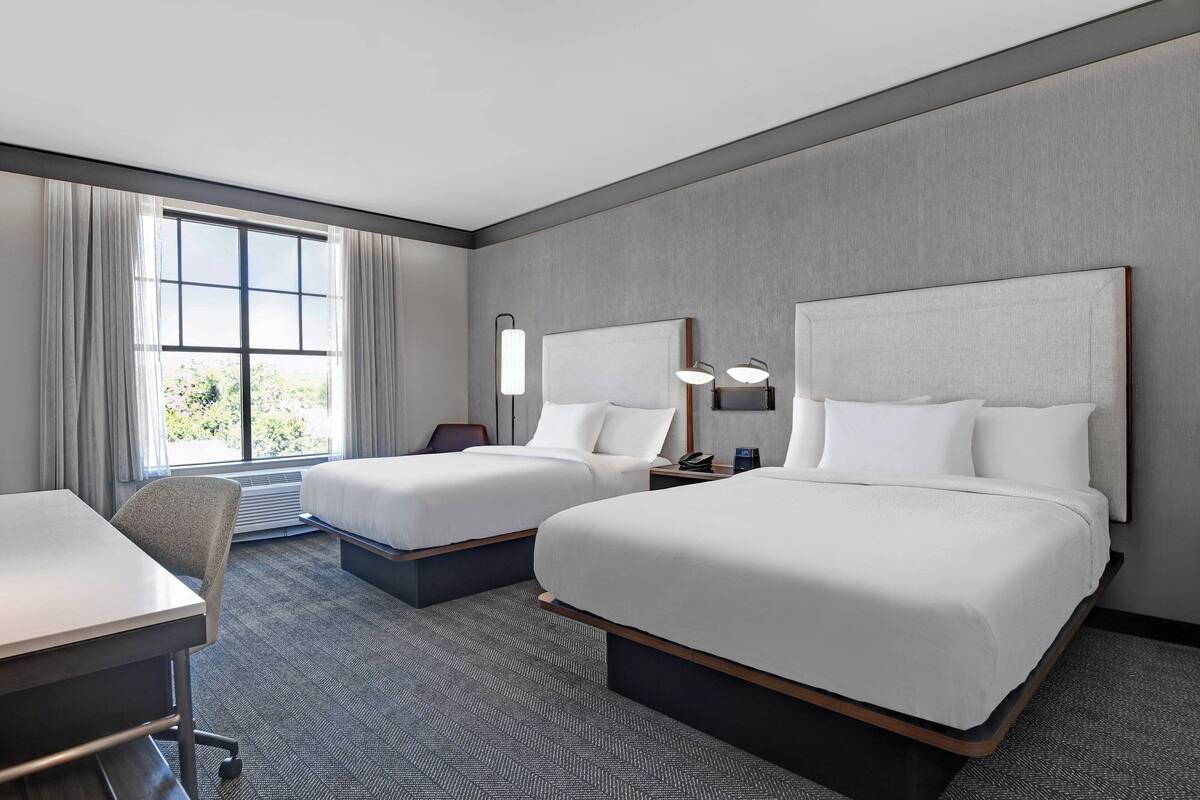 Habitación de hotel con dos camas, un escritorio y una silla.
