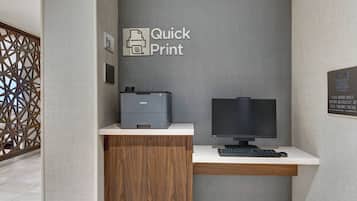 A reception desk with a printer, computer monitor, and keyboard.
