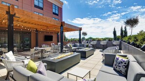 An outdoor patio with seating, a fire feature, and a building in the background. - Courtyard by Marriott Manhattan Aggieville (Manhattan)