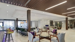 A spacious lobby with high ceilings, modern furniture, and a bar area. - Courtyard by Marriott Manhattan Aggieville (Manhattan)