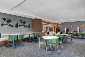 A modern dining area with green chairs, white tables, and a grey carpet. - Courtyard by Marriott Manhattan Aggieville (Manhattan)