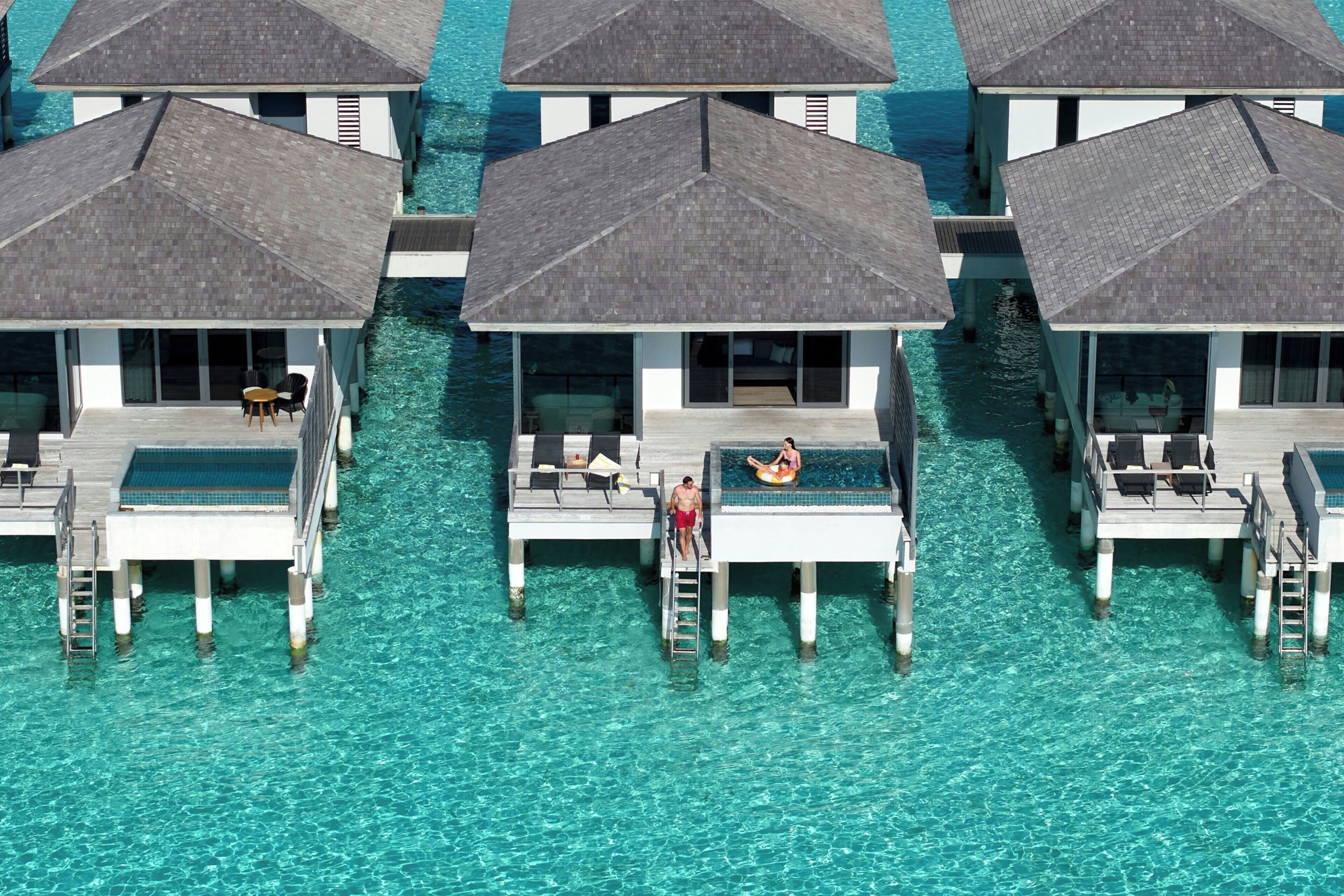 Overwater bungalows with infinity pools, connected by walkways, and clear turquoise water.