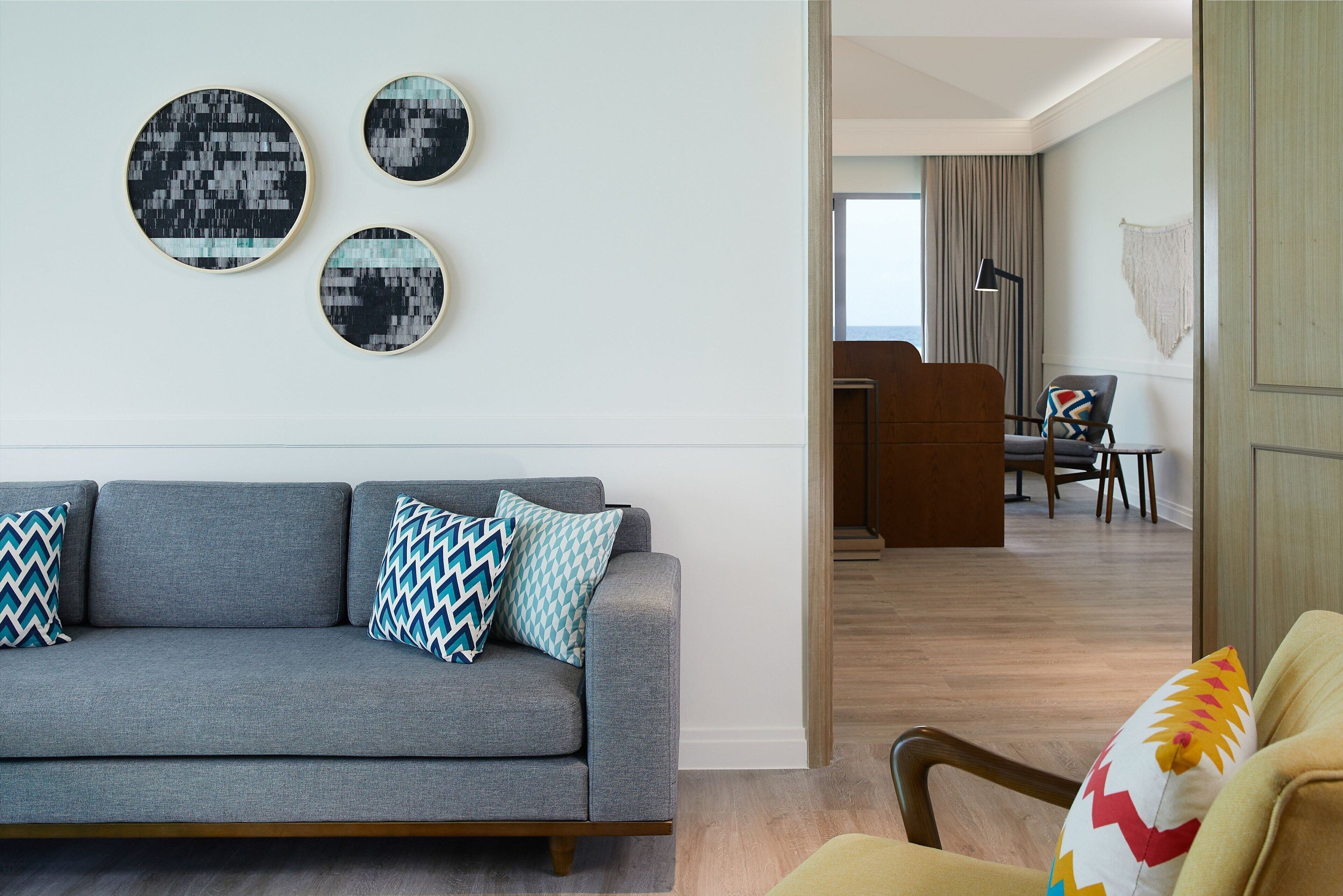 A modern living room with a grey sofa, patterned cushions, and three wall-mounted circular artworks.
