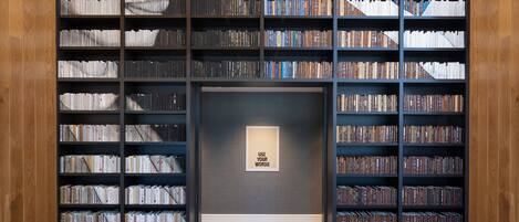 A library with bookshelves filled with books, a framed quote on the wall, and wooden paneling on the walls.
